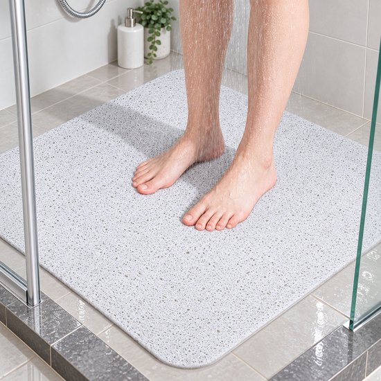 Persoon staat op een witte antislip douchemat met loofah-textuur in een inloopdouche.