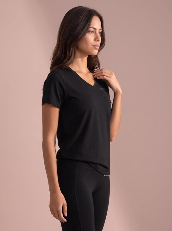 Vrouw in zwart sportshirt met V-hals en logo op de borst.