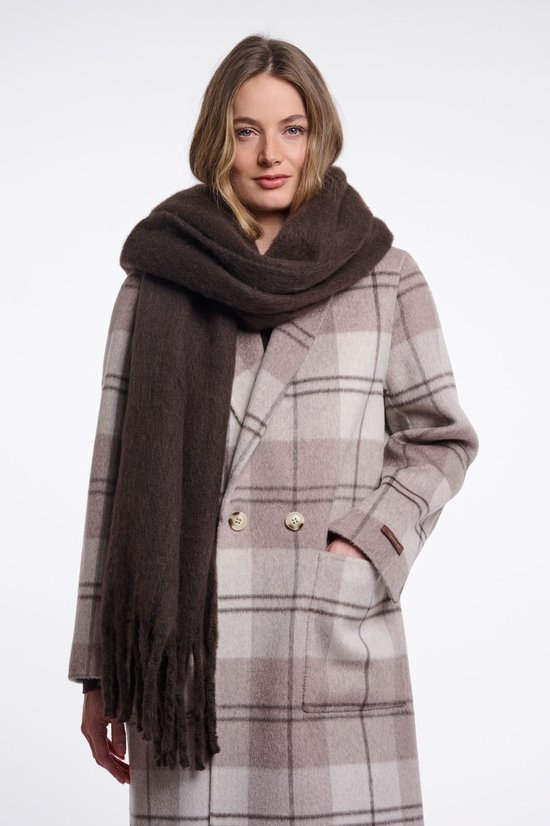 Model met een bruine sjaal om een beige geruite jas met bruine knopen.