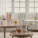 Een verzameling glazen met verticale ribbels en een diamantpatroon aan de basis, gevuld met diverse dranken.