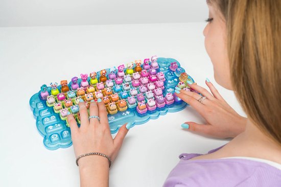 Vrouw speelt met een blauw Clickeez toetsenbord gevuld met felgekleurde figuurtjes.