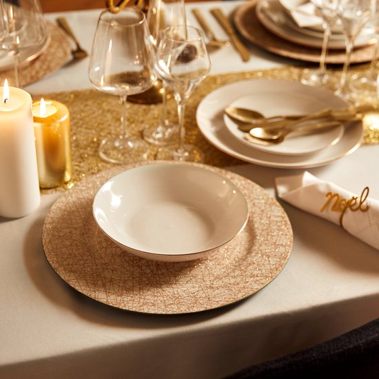 Gedekte tafel met borden met koperkleurig kriskras patroon, gouden bestek en servetring met 'noel'.