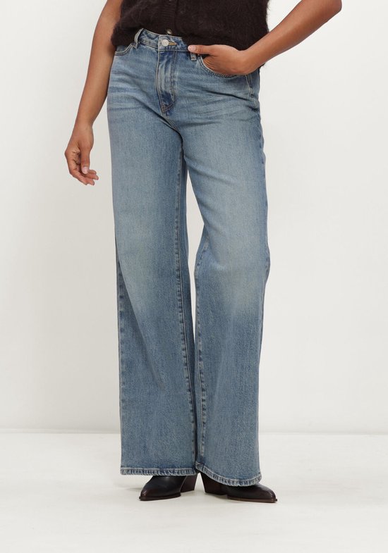 Model draagt een lichtblauwe Circle Of Trust jeans met wijde pijpen en een hoge taille.