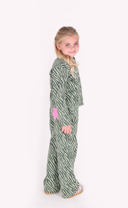Meisje met blond haar, staand opzij, met een groen met donkergroene zebraprint set.