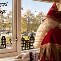 Raamsticker van silhouetten van huizen met Sinterklaasfiguren en sterren. Met de tekst 'Kom erbij!'