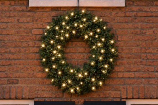 Groene kerstkrans met 80 warm witte LED lampjes, gemonteerd aan een bakstenen muur.