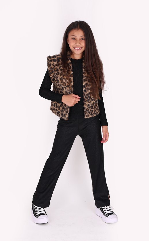 Meisje met lang bruin haar, draagt zwart shirt, panterprint gilet en zwarte broek.