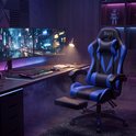 Een comfortabele zwarte en blauwe gamingstoel met uitschuifbaar voetensteun staat bij een bureau met dubbele computerschermen.