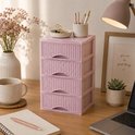 Roze ladeblokje op een bureau, naast een vaas met bloemen en een mok koffie. Het ladeblok heeft een rotan-look textuur en gebogen handgrepen.