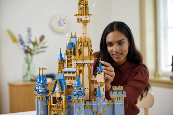 Een vrouw bouwt aan het LEGO Disney Kasteel, focust op de details van de toren.