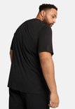 Man, van achteren gezien, draagt een zwarte PUMA t-shirt met korte mouwen.