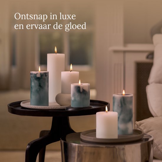Set van brandende witte en marmergroene kaarsen op tafels in een sfeervolle kamer.