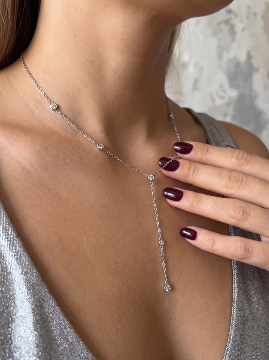 Zilverkleurige Y-ketting met fijne schakels en steentjes, gedragen bij een zilveren top.