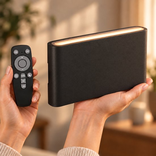 Zwarte, rechthoekige oplaadbare wandlamp met warme lichtbalk, vastgehouden met een afstandsbediening met timerinstellingen.