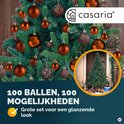 Kerstboom vol koperkleurige ballen. Tekst: Casaria, 100 ballen, 100 mogelijkheden.