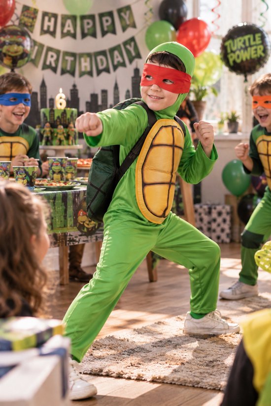 Kind in groen Ninja Schildpad kostuum met rood masker en schild op de rug, vechtend op een verjaardagsfeest.