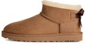 Zijaanzicht van een cognackleurige suède UGG Ultra Mini laars, voorzien van een crèmekleurige voering en strikdetail.