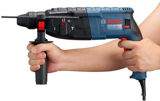 Iemand houdt een blauwe Bosch Professional boorhamer vast met beide handen.
