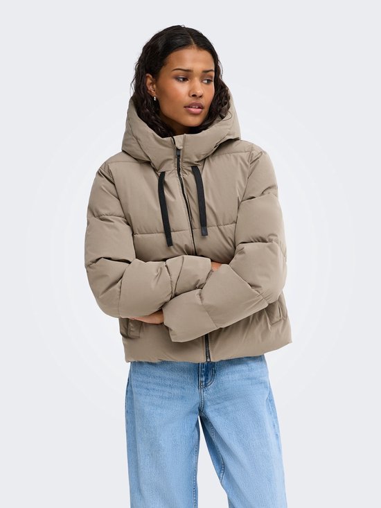 Model met gekruiste armen draagt een beige pufferjas met capuchon en zwarte ritssluiting.