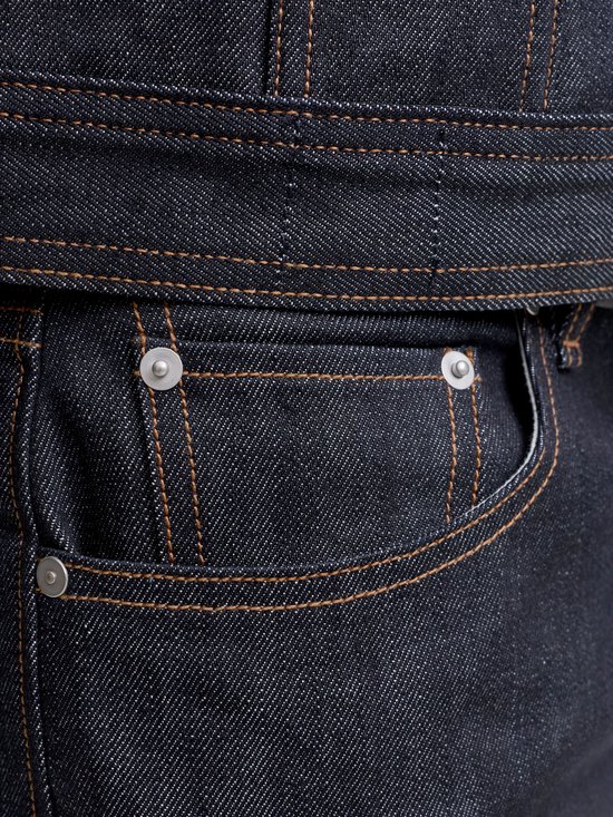 Close-up van de zak van een donkerblauwe jeans met zilveren klinknagels en oranje stiksels.