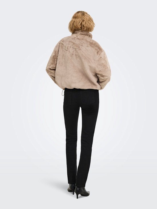 Achteraanzicht van model in beige imitatiebont jack en zwarte broek met zwarte enkellaarsjes.