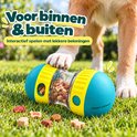Blauwe en gele snackbal op gras. Een hond heeft zijn poot erop.