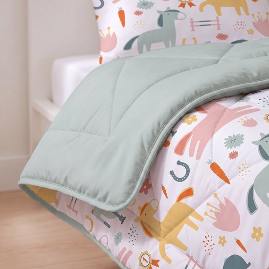 Detailopname van de hoek van een dekbed met paardenprint en effen zachtgroene accenten op een wit bed.