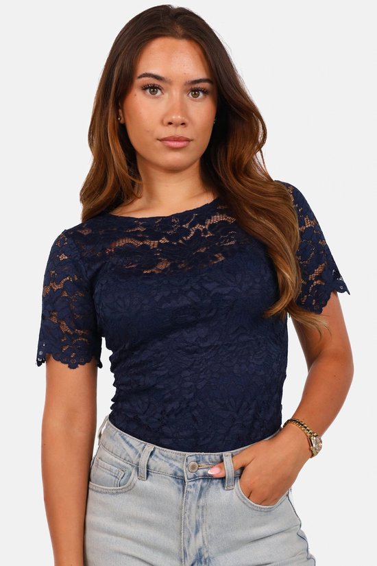 Close-up van een donkerblauwe kanten top met korte mouwen en gedetailleerd bloemmotief, gedragen in een lichtblauwe jeans.