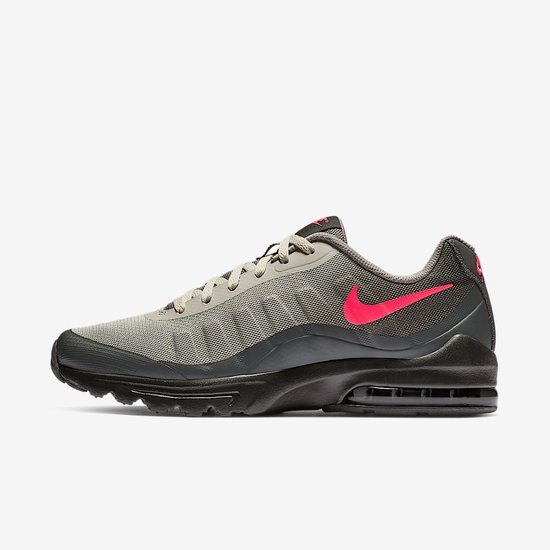 Zijaanzicht van de binnenkant van een grijze Nike sneaker met roze swoosh en zwarte zool.