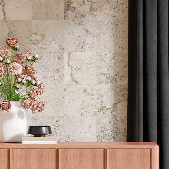Beige wandtegels met natuursteenstructuur, gecombineerd met een boeket roze bloemen en een houten meubel.