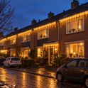 Rijtjeshuis in de avond versierd met sfeervolle warm witte Springos ijspegelverlichting langs de dakgoot.
