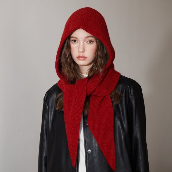 Model met bruin haar draagt een rode, geribbelde gebreide sjaal met capuchon en een zwarte leren jas.