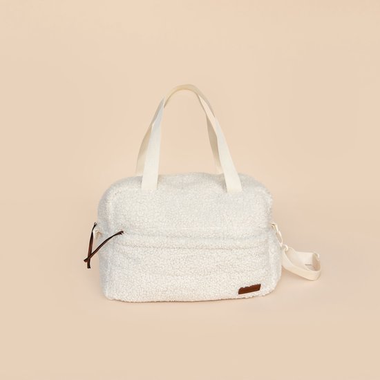 Sac à langer blanc en teddy avec anses crème et détails marron. Le sac a une bandoulière.