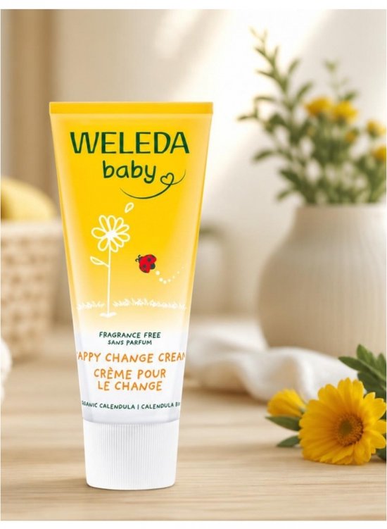 Tube Weleda billenbalsem met bloemen en lieveheersbeestje op houten tafel.