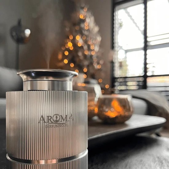 Zilverkleurige, geribbelde Aroma diffuser in een sfeervolle woonkamer met kerstverlichting.
