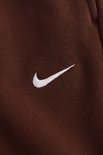 Detail van het witte Nike logo op een bruine Nike broek.