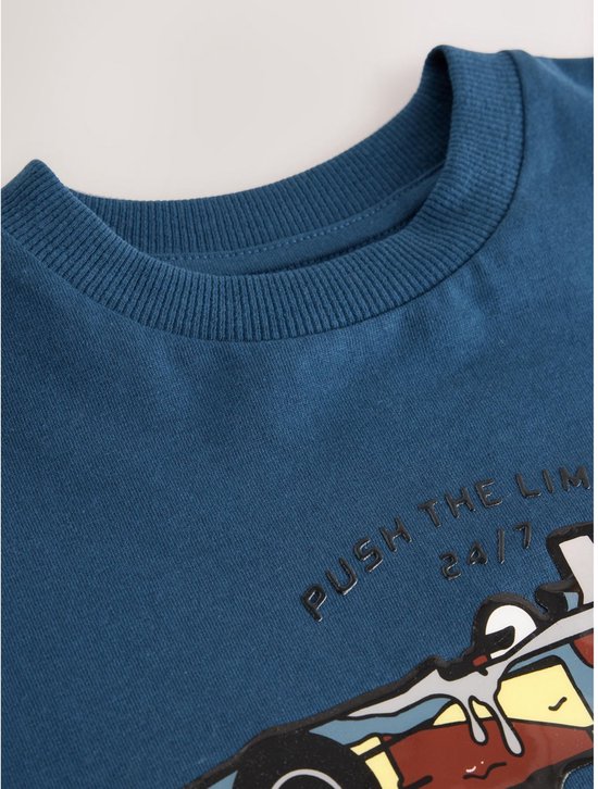 Blauwe top met ronde hals en de tekst "PUSH THE LIMITS 24/7" boven een kleurrijke raceauto-print.