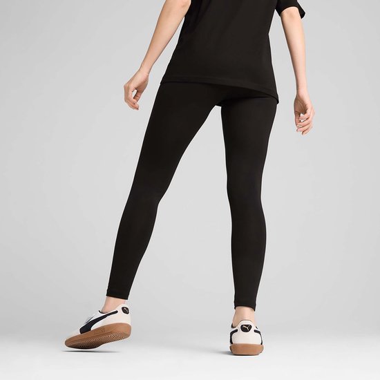 Een vrouw in zwarte PUMA legging en sneakers, staand.