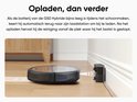 Zwarte robotstofzuiger keert terug naar het laadstation aan de muur om op te laden.