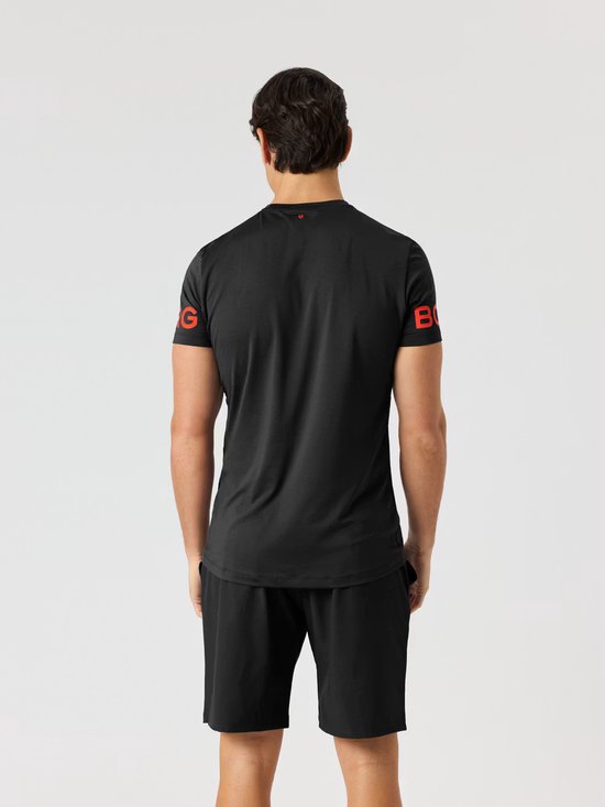 Man in zwart sportshirt met rode Björn Borg letters op de mouwen, achterkant. Zwarte sportshort.