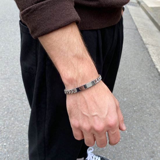 Zilverkleurige roestvrijstalen ID-plaatarmband met een dikke schakelketting om een mannenpols.