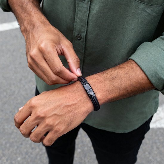 Zwarte gevlochten leren armband met magneetsluiting van Lucleon om de pols van een man.