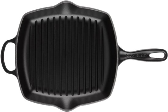 Zwarte vierkante gietijzeren grillpan met ribbels, handvat en Le Creuset logo, op zwarte achtergrond.