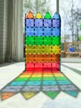 Een regenboog van transparante, veelkleurige Magna-Tiles torens en de schaduw ervan.