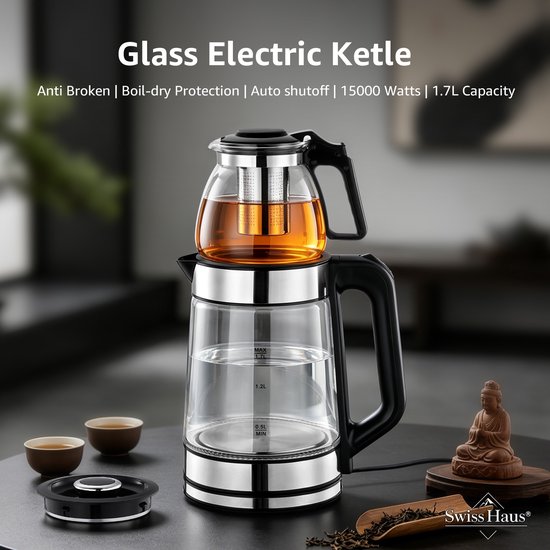 Glazen waterkoker met een theepot bovenop, gevuld met amberkleurige thee, op een donkere tafel met theekopjes en theebladeren. De waterkoker heeft roestvrijstalen accenten en een zwarte handgreep.