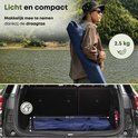 Man draagt blauwe campingstoel in draagtas, 2.5 kg, past in auto.