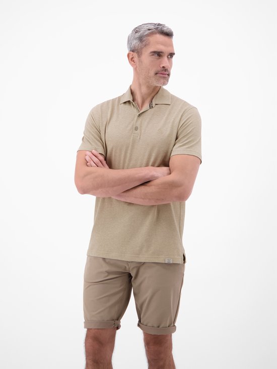 Man met gekruiste armen in een lichtbruin gemêleerd poloshirt en een beige short.