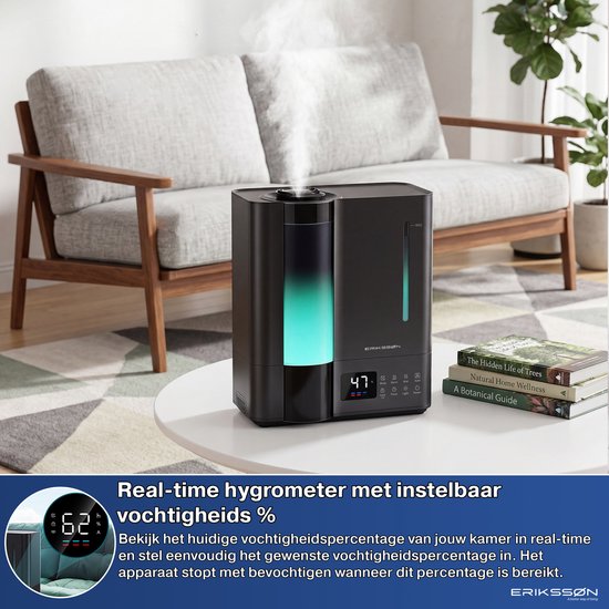 Zwarte Erikssøn luchtbevochtiger met groen oplichtende tank, die mist uitstoot, op een salontafel in een woonkamer met een bank.