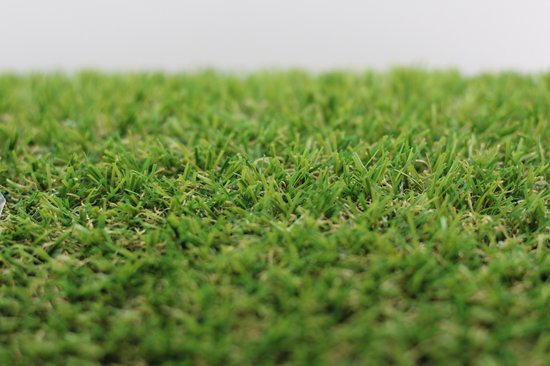 Close-up van een grasmat met scherpe groene sprieten en wazige achtergrond.