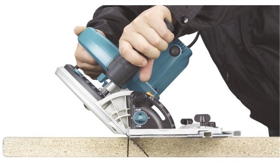 Een hand wordt gebruikt om een Makita invalcirkelzaag te bedienen op een stuk hout.